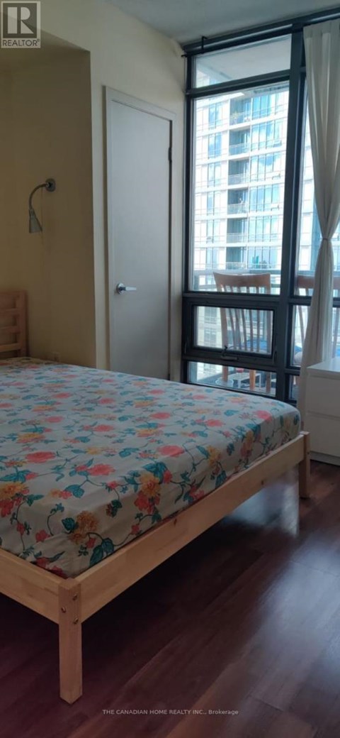 A bedroom with a large bed and a window overlooking a building.