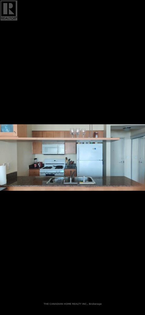A modern kitchen with a refrigerator, microwave, and oven.
