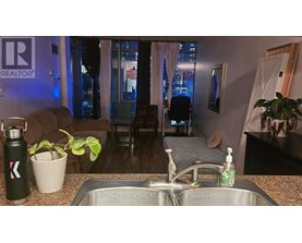 A kitchen with a sink and a window with a view of the city.