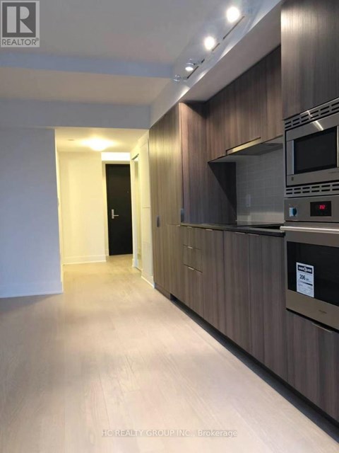 A modern kitchen with dark wood cabinets and stainless steel appliances.