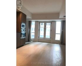 A spacious room with a kitchen area and large windows.
