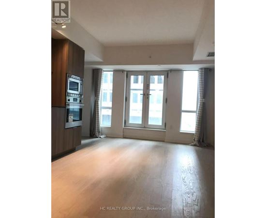 A spacious room with a kitchen area and large windows.