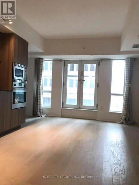 A spacious room with a kitchen area and large windows.