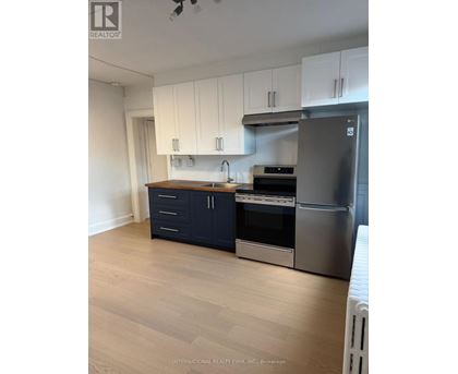 A kitchen with white cabinets and a stainless steel refrigerator.