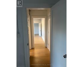 A hallway with white walls and wooden floors.