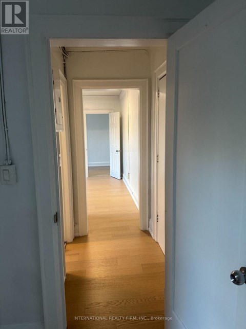 A hallway with white walls and wooden floors.