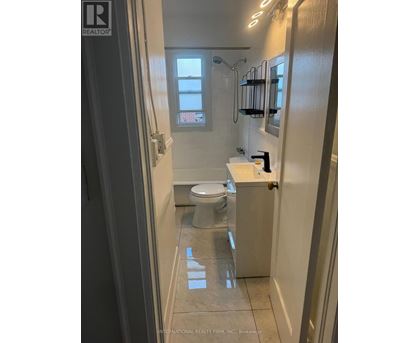 A white toilet in a small bathroom with a shower.