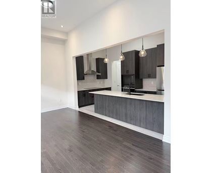 A modern kitchen with dark wood floors and a white countertop.