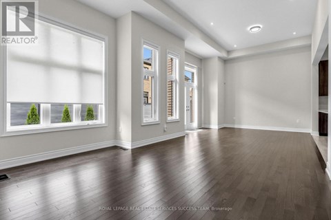 A spacious room with wooden flooring and a large window.