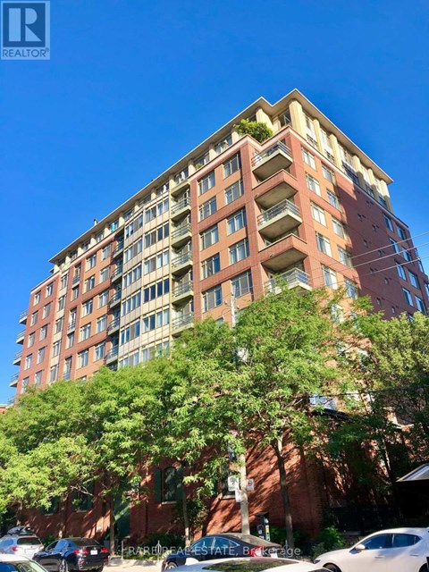 A tall apartment building with a parking lot in front.
