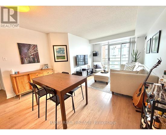 A living room with a wooden dining table and chairs, a couch, and a guitar on the floor.