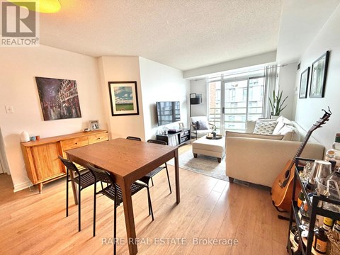A living room with a wooden dining table and chairs, a couch, and a guitar on the floor.