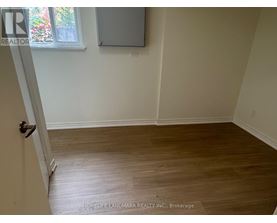 A room with wooden flooring and a door leading to another room.