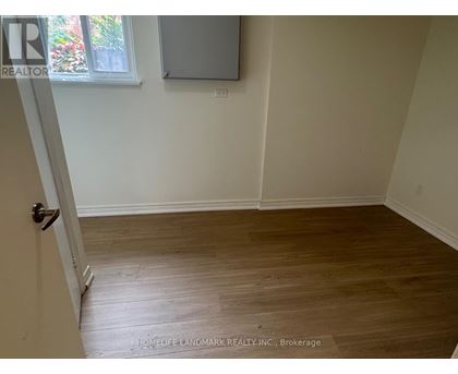 A room with wooden flooring and a door leading to another room.