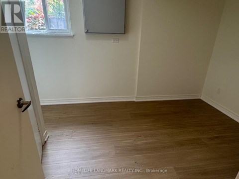 A room with wooden flooring and a door leading to another room.