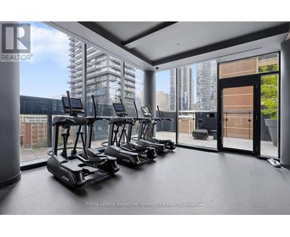 A room with a row of treadmills and a view of the city outside the window.