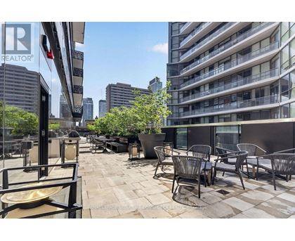 A patio with chairs and tables is in front of a tall building.