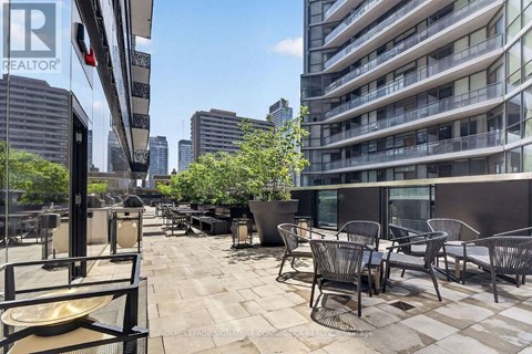 A patio with chairs and tables is in front of a tall building.