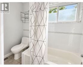 A white toilet sits next to a white shower curtain in a bathroom.