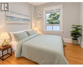 A bedroom with a bed, two lamps, a painting, and a potted plant.
