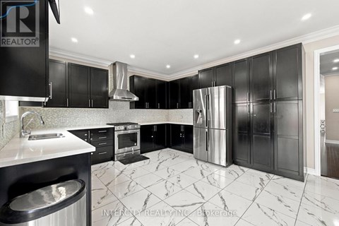 A modern kitchen with black cabinets and marble flooring.