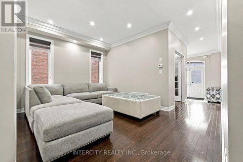 A well-lit bedroom with a grey sofa and a white bed.