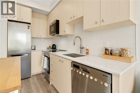 A kitchen with a stainless steel dishwasher and wooden cabinets.