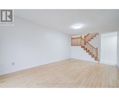 A room with a wooden floor and a staircase.