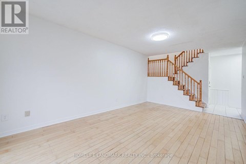 A room with a wooden floor and a staircase.