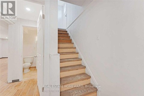 A staircase with wooden steps and a white wall.