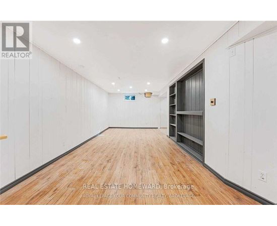 A long, empty room with wood flooring and white walls.