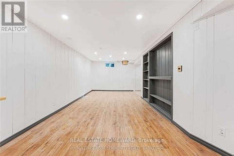 A long, empty room with wood flooring and white walls.