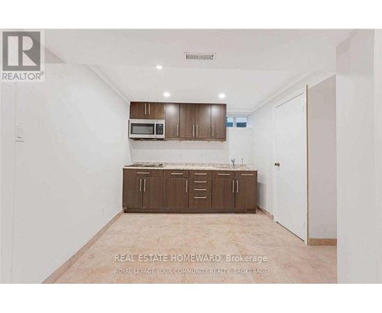 A real estate advertisement showing an empty room with a kitchenette.
