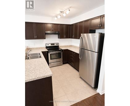 A kitchen with a refrigerator, oven, and sink.
