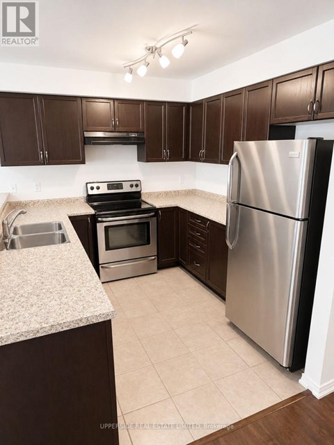 A kitchen with a refrigerator, oven, and sink.