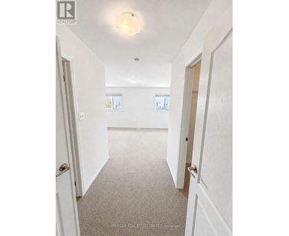 A hallway with white walls and carpeted floor.