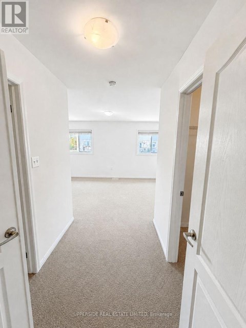 A hallway with white walls and carpeted floor.