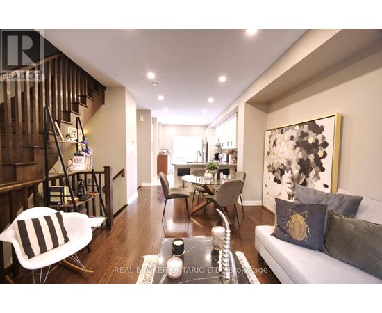 A living room with a grey couch and a painting on the wall.