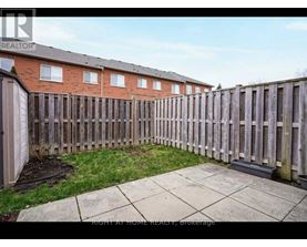 A backyard with a wooden fence and a brick building in the background.