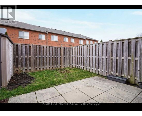 A backyard with a wooden fence and a brick building in the background.
