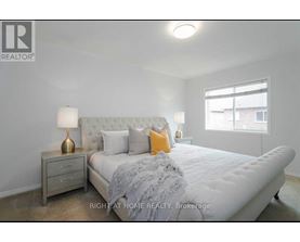 A bedroom with a large bed, a nightstand with a lamp, and a window.