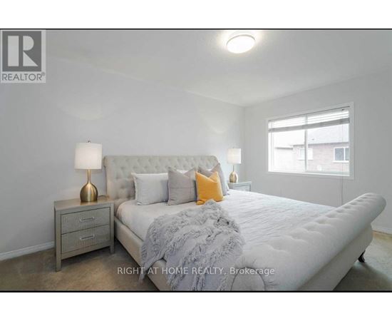 A bedroom with a large bed, a nightstand with a lamp, and a window.