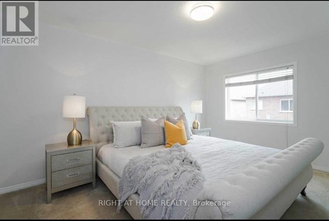 A bedroom with a large bed, a nightstand with a lamp, and a window.