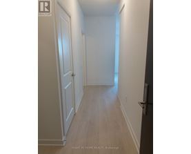 A long hallway with white walls and wood floors.
