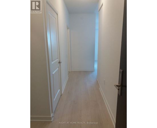 A long hallway with white walls and wood floors.