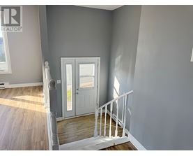 A room with a white door and a staircase.