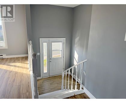 A room with a white door and a staircase.