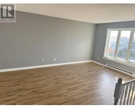 A room with wooden flooring and a window overlooking a street.