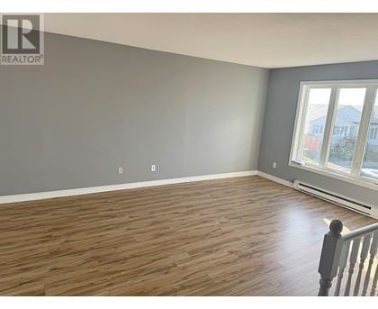 A room with wooden flooring and a window overlooking a street.