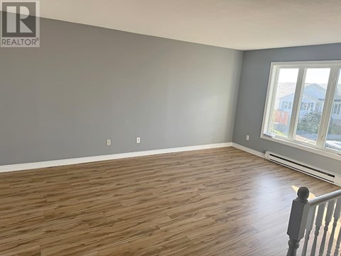 A room with wooden flooring and a window overlooking a street.